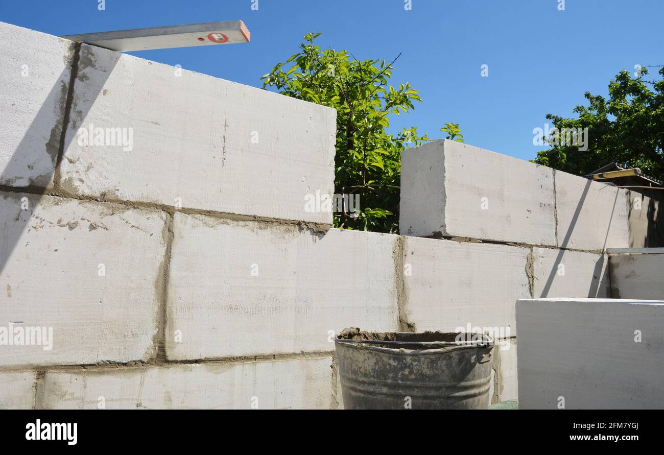 Concrete bricklaying, concrete masonry of a new house. Building a wall from autoclaved concrete blocks using mortar, a trowel and a spirit level. Stock Photo