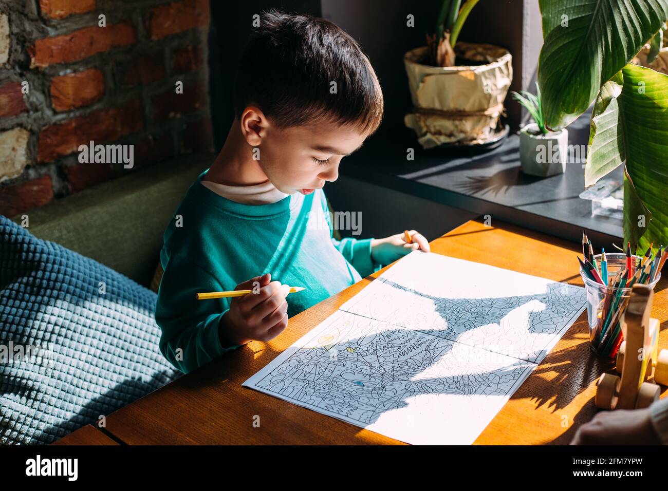 Portrait of a cute happy preschool boy at home or in a cafe draws Stock ...