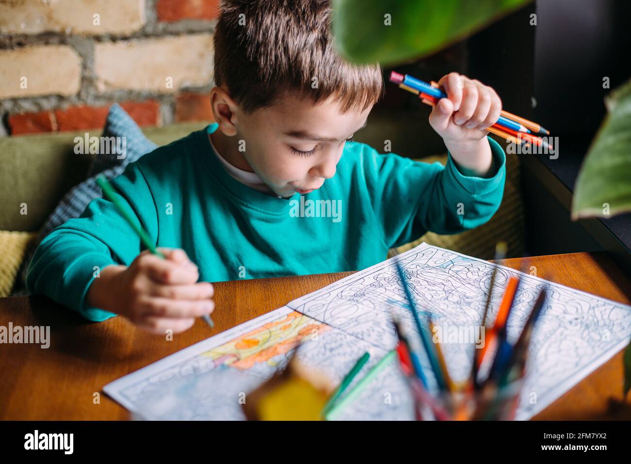 Portrait of a cute happy preschool boy at home or in a cafe draws Stock ...