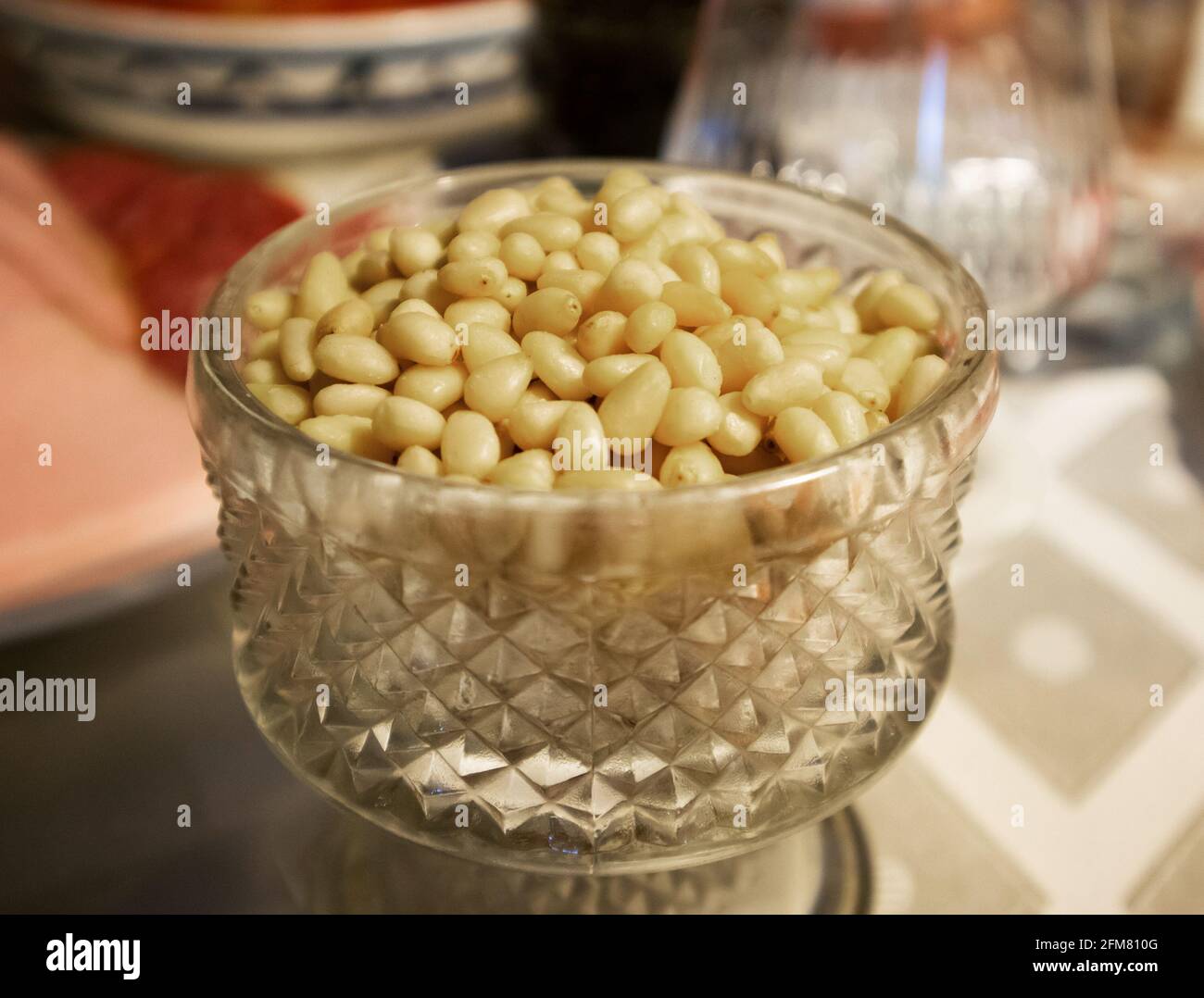 Pile of peeled kernels of cedar nuts in a fluted crystal vase Stock Photo