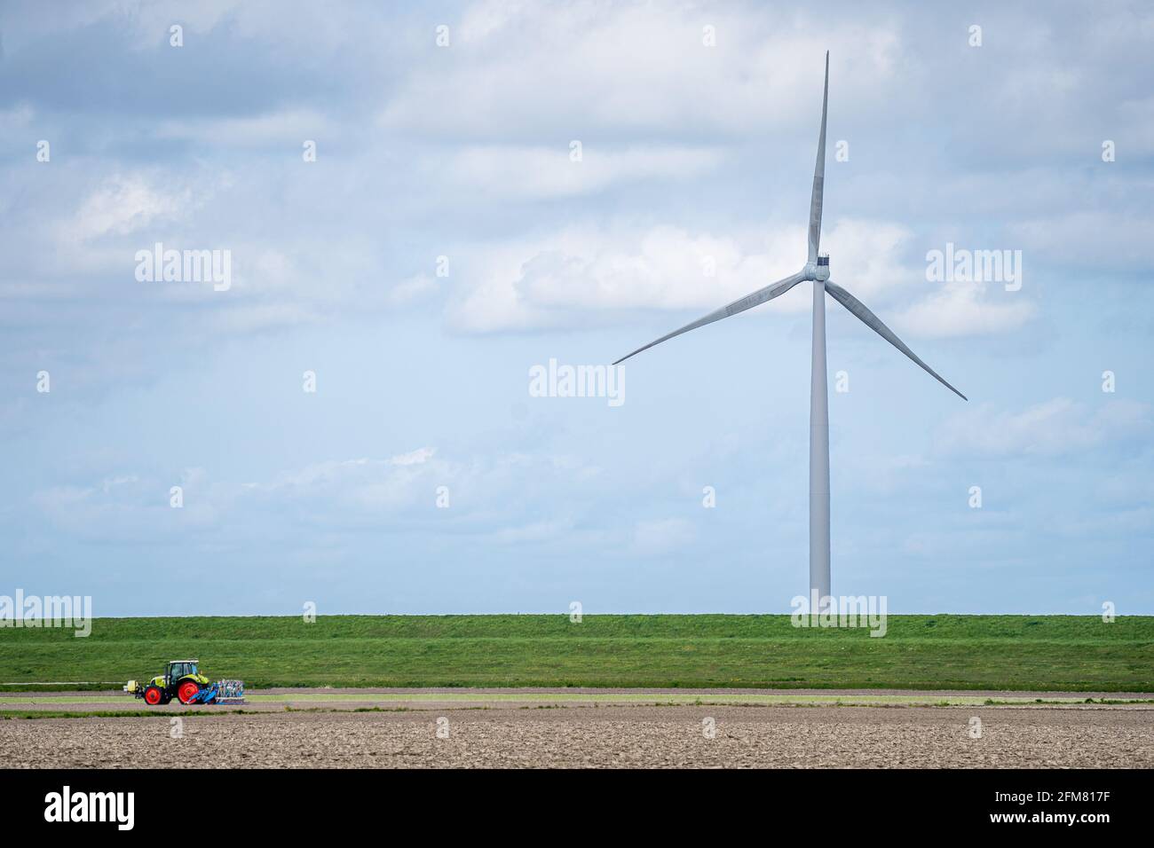 Wind turbines in a green field under a cloudy sky Stock Photo - Alamy
