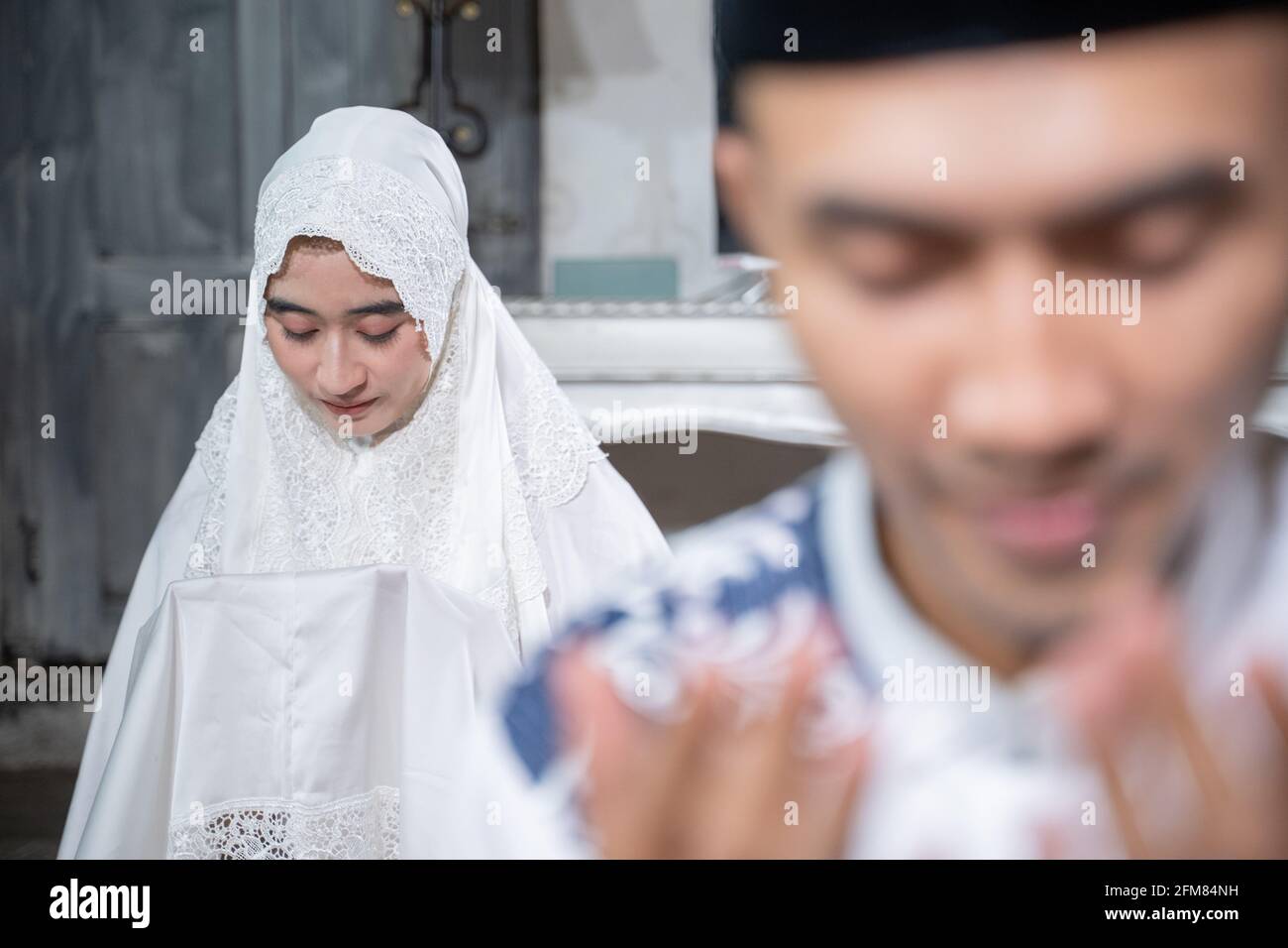 muslim husband and wife praying jamaah together at home Stock Photo