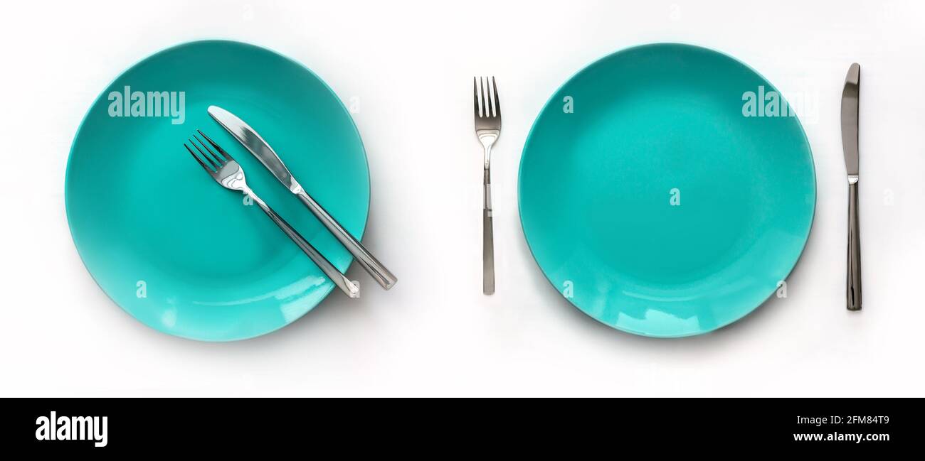 Served plates with cutlery. Empty green plates and stainless knives and forks isolated on white background. Top view. Studio shot Stock Photo