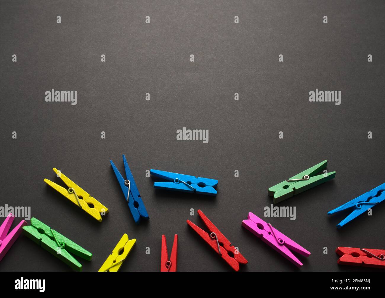Mini colorful wooden craft pegs flat lay on black dark grunge texture pattern abstract background. Free space for your design. Top view, no people. Stock Photo