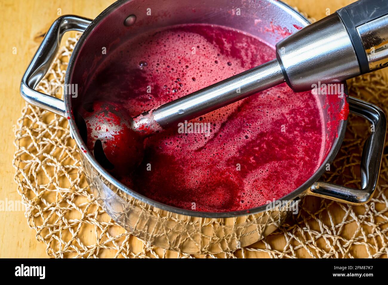 Immersion blender in pot with beetroot soup. Preparing beetroot soup. Stock Photo