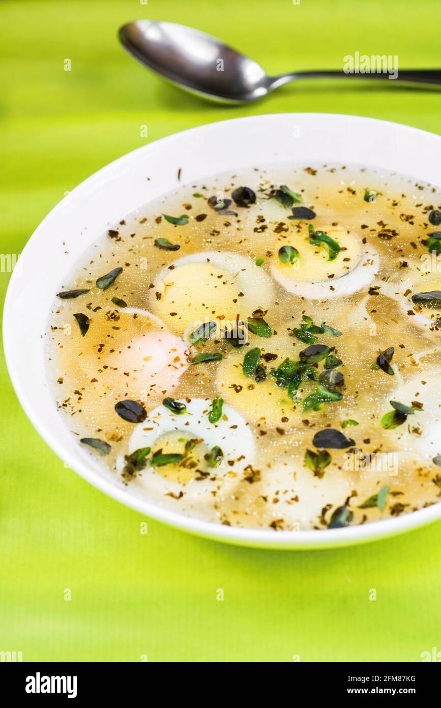 Smoked broth with sliced boiled egg and herb in part of white plate on ...