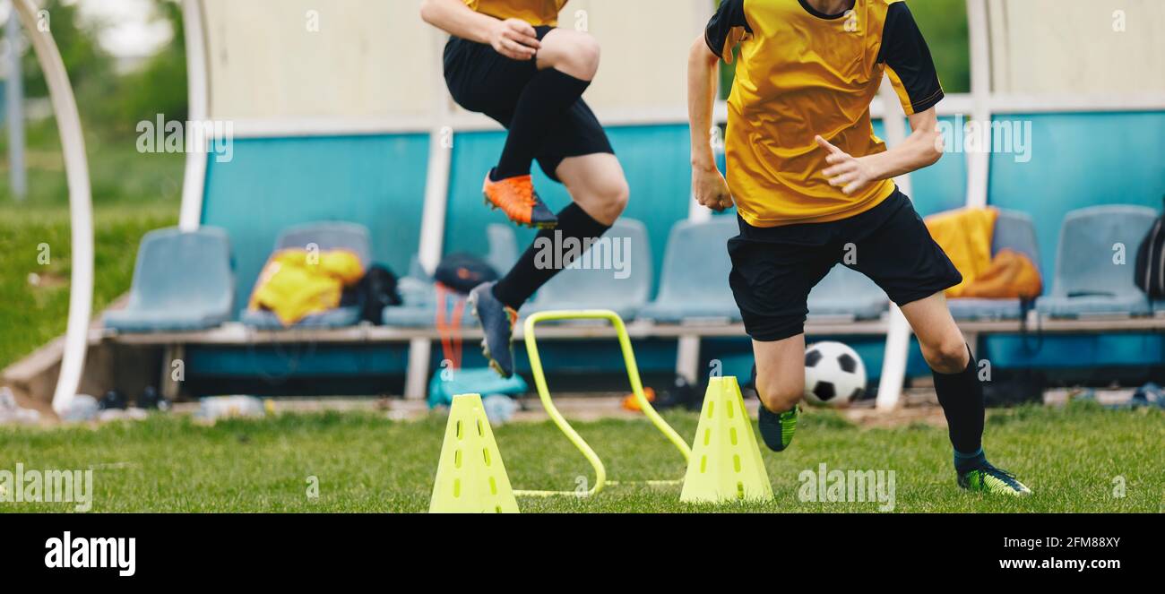 Two young athletes on soccer training drill. Football camp practice activities for players. Two boys running on training football obstacle course Stock Photo