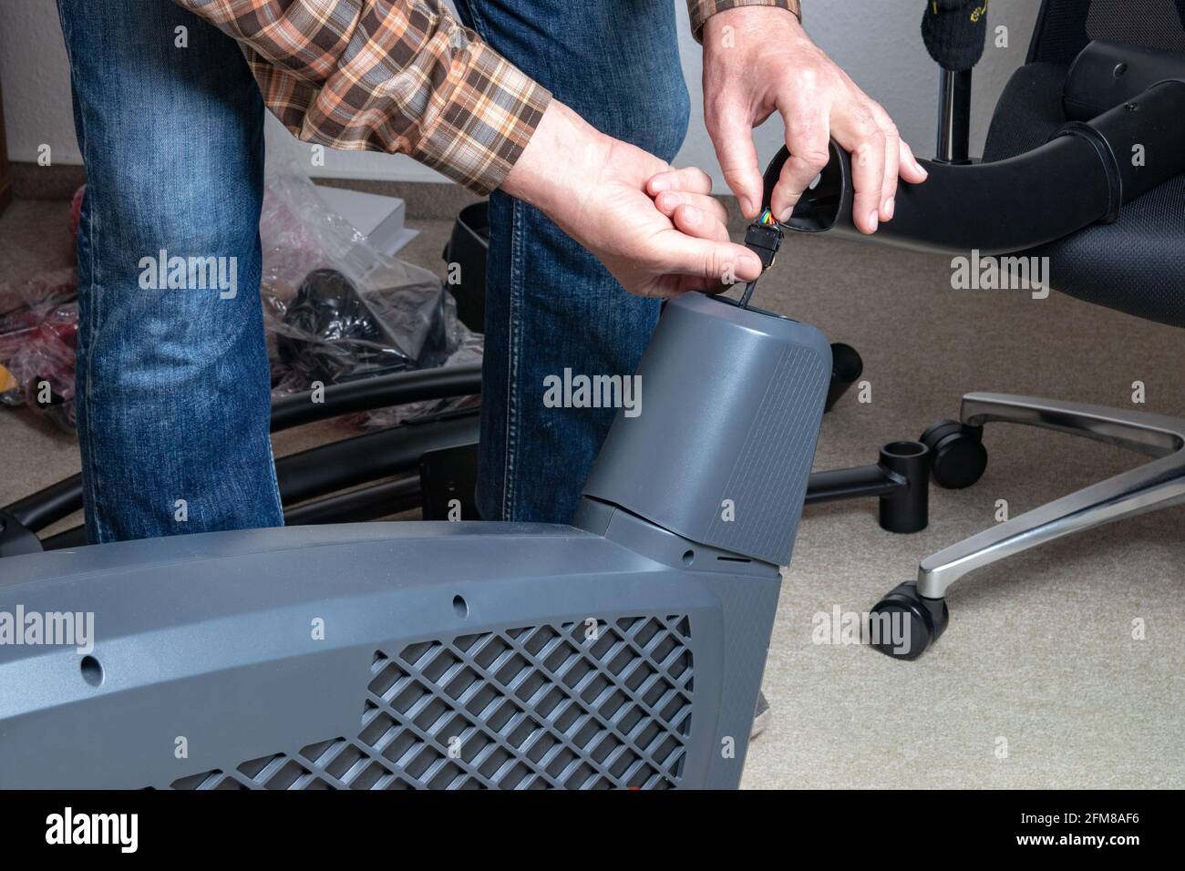 When assembling a crosstrainer, the service technician connects the computer to the electronics of the main unit using an electrical plug connector. F Stock Photo
