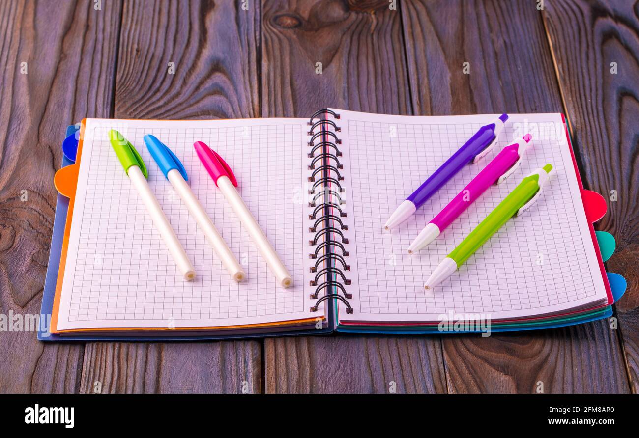 Diary (notebook) and colored pens on wooden background. Stock Photo