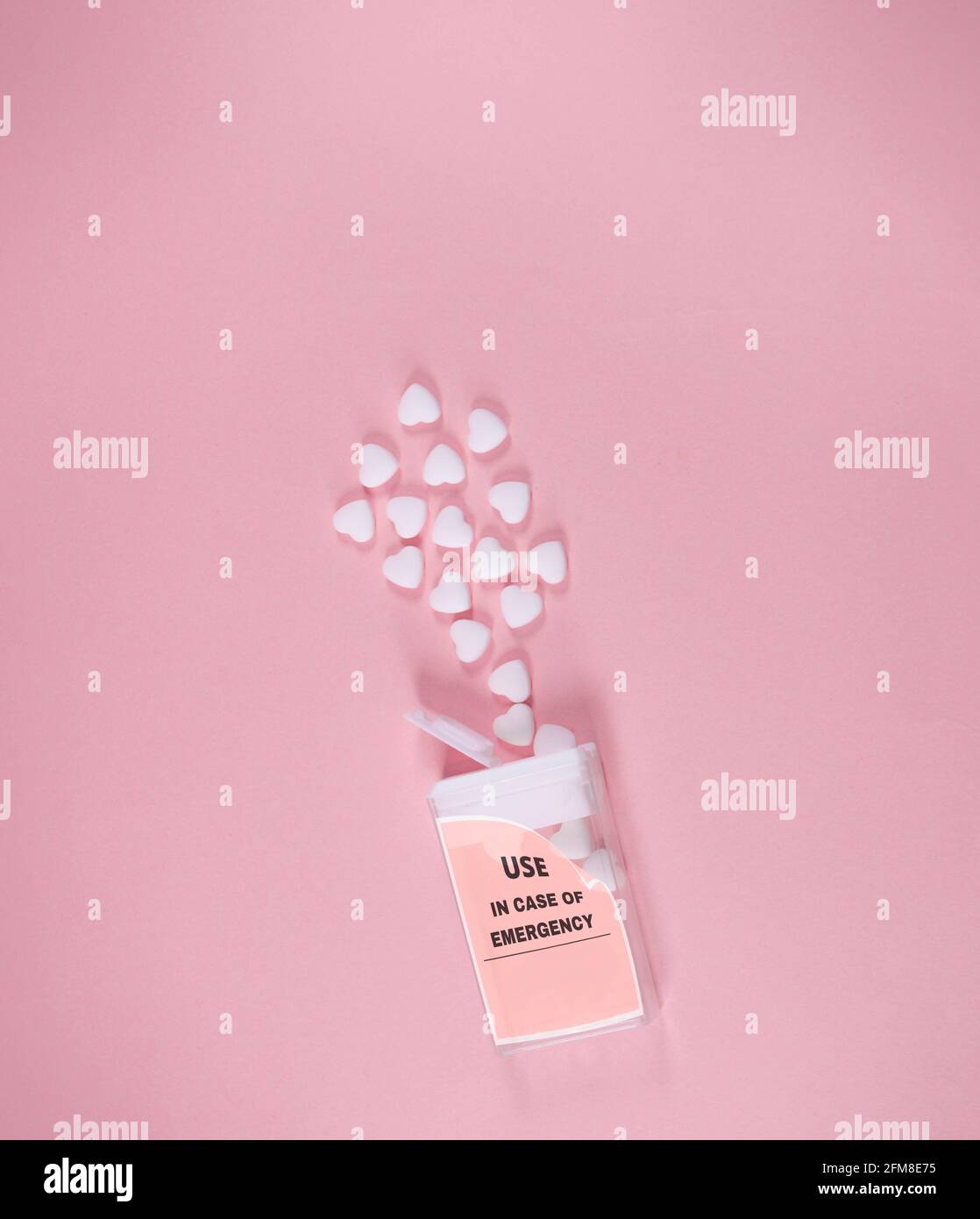 Box with use in emergency writing. Small white hearts coming out. On soft pink background. Minimal abstract Valentines, Mother's day concept. Stock Photo