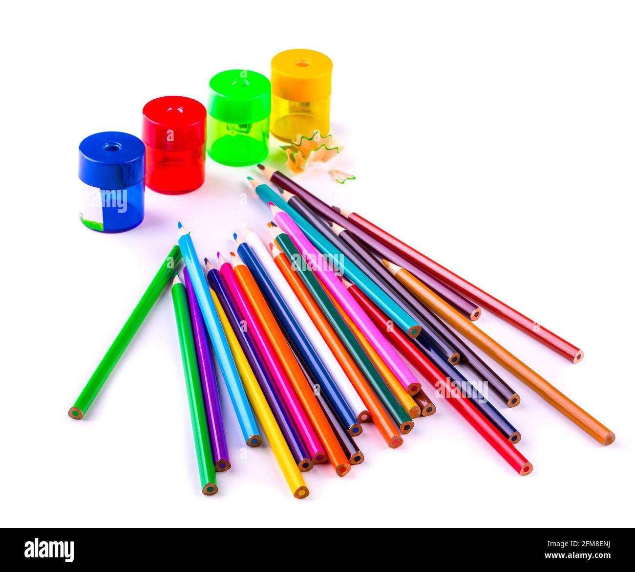 some colored pencils of different colors and a pencil sharpeners and pencil shavings on a white