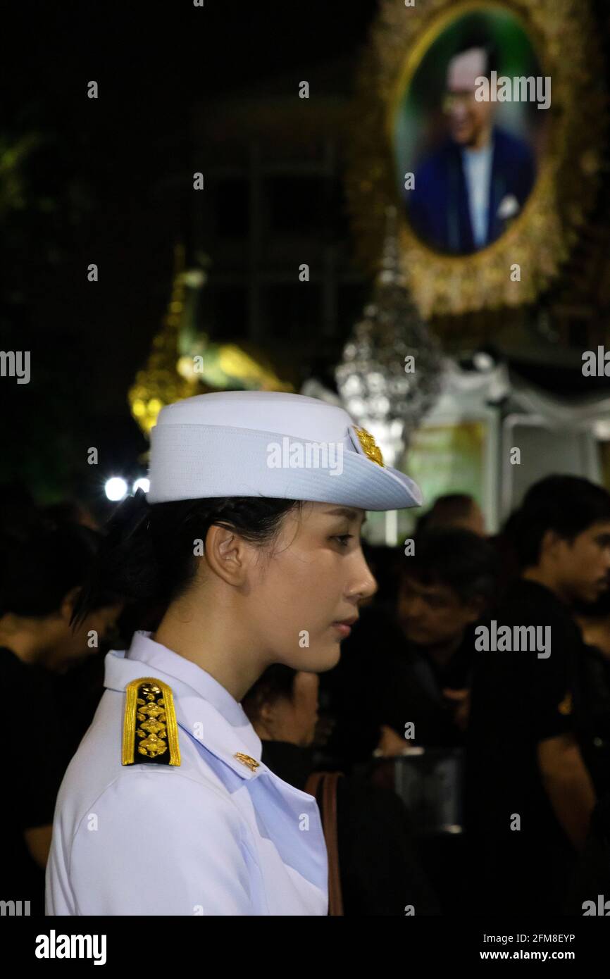 Government officer in uniform in front of photograph at funeral of King