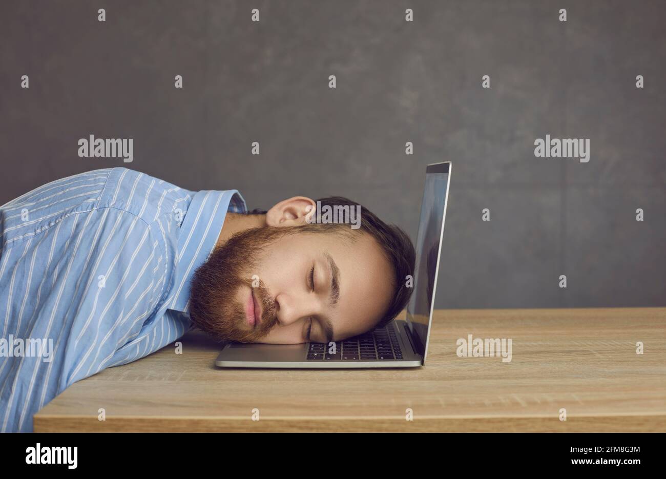 Tired business man office worker sleeping on laptop keyboard studio shot Stock Photo
