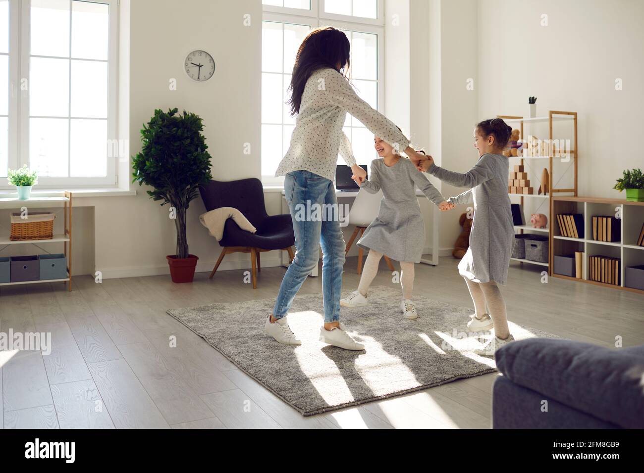 Funny active mother dancing together with daughters children in home living room Stock Photo
