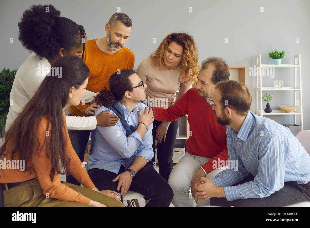 Young patient accepting help from diverse men and women in a group therapy session Stock Photo