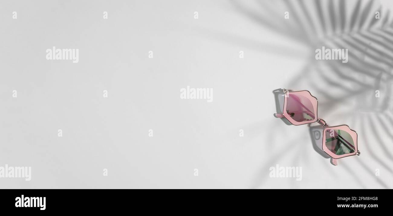 Funky sunglasses in pink lips shape on gray background with tropical shades, copy space,banner Stock Photo