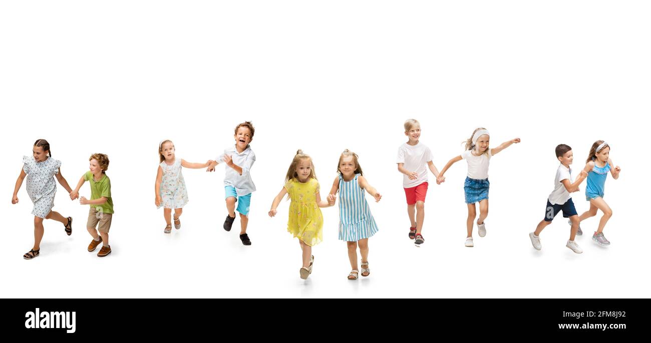 Group of happy school kids or pupils running in colorful casual clothes on white studio background. Creative collage. Stock Photo