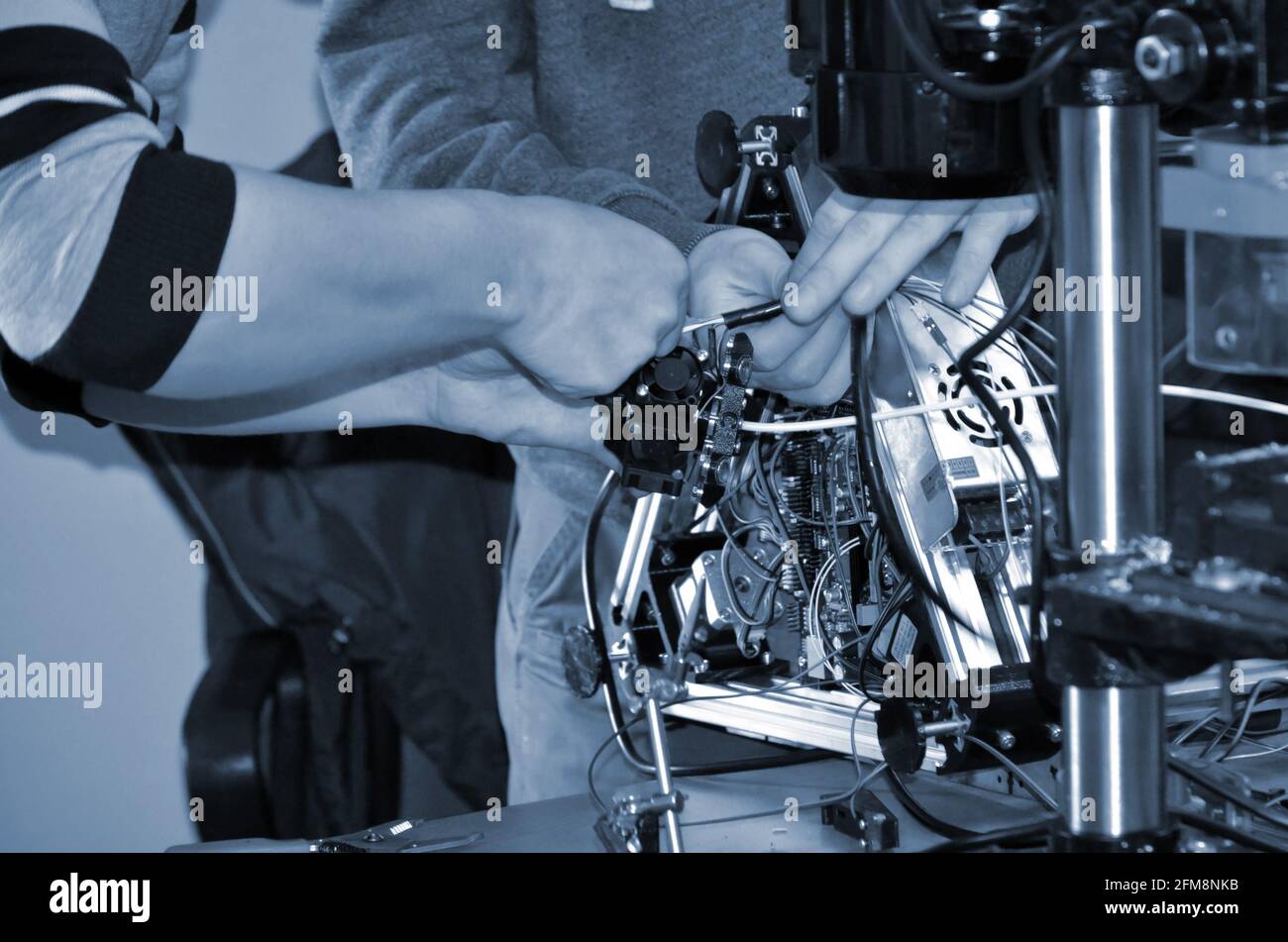 Two male masters work in the workshop with electronics, wires, 3d printer. Stock Photo
