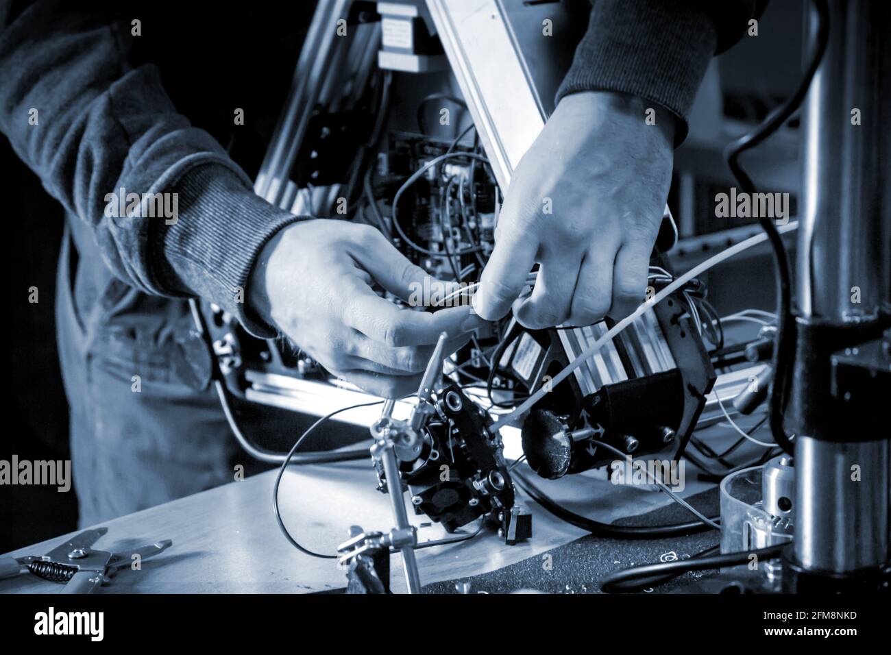 Two male masters work in the workshop with electronics, wires, 3d printer. Stock Photo