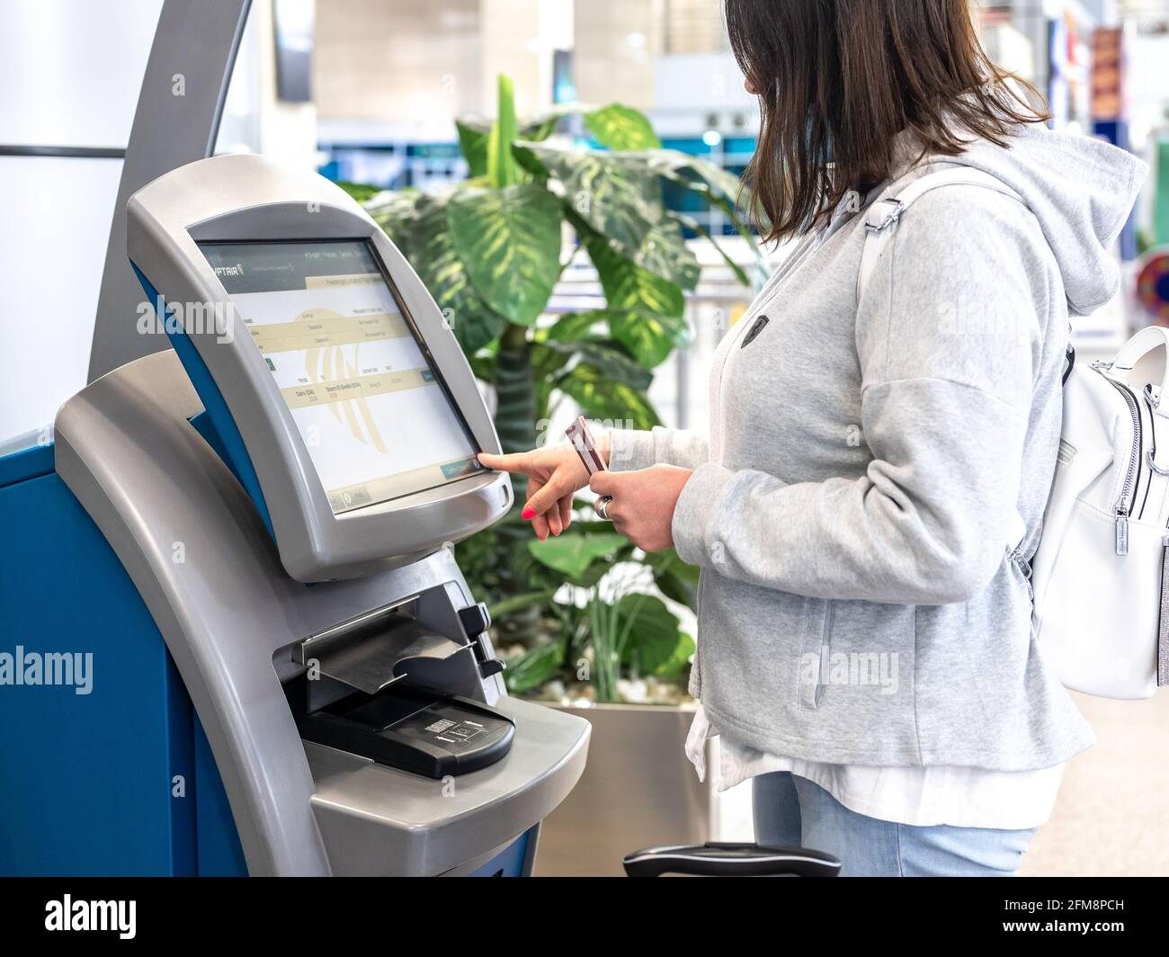 CAIRO, EGYPT - May 06, 2021: EGYPTAIR airline counter for self-check-in at Cairo airport. Woman using Self service machine at airport for check in, pr Stock Photo