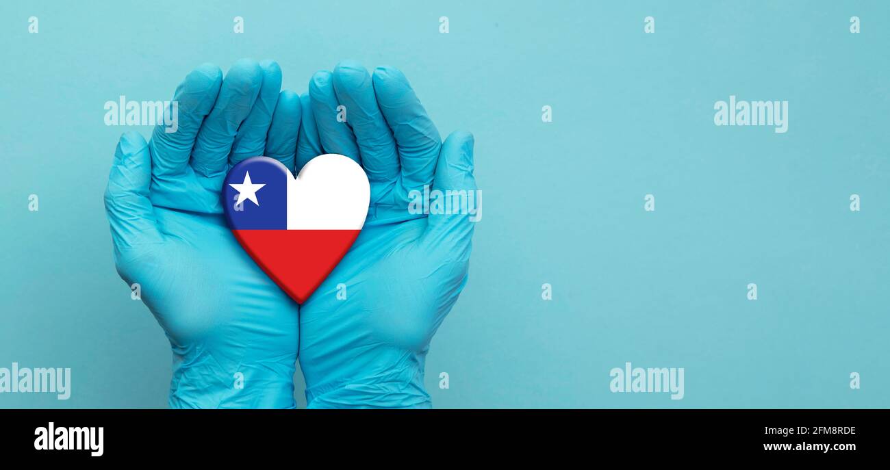 Doctors hands wearing surgical gloves holding Chile flag heart Stock Photo