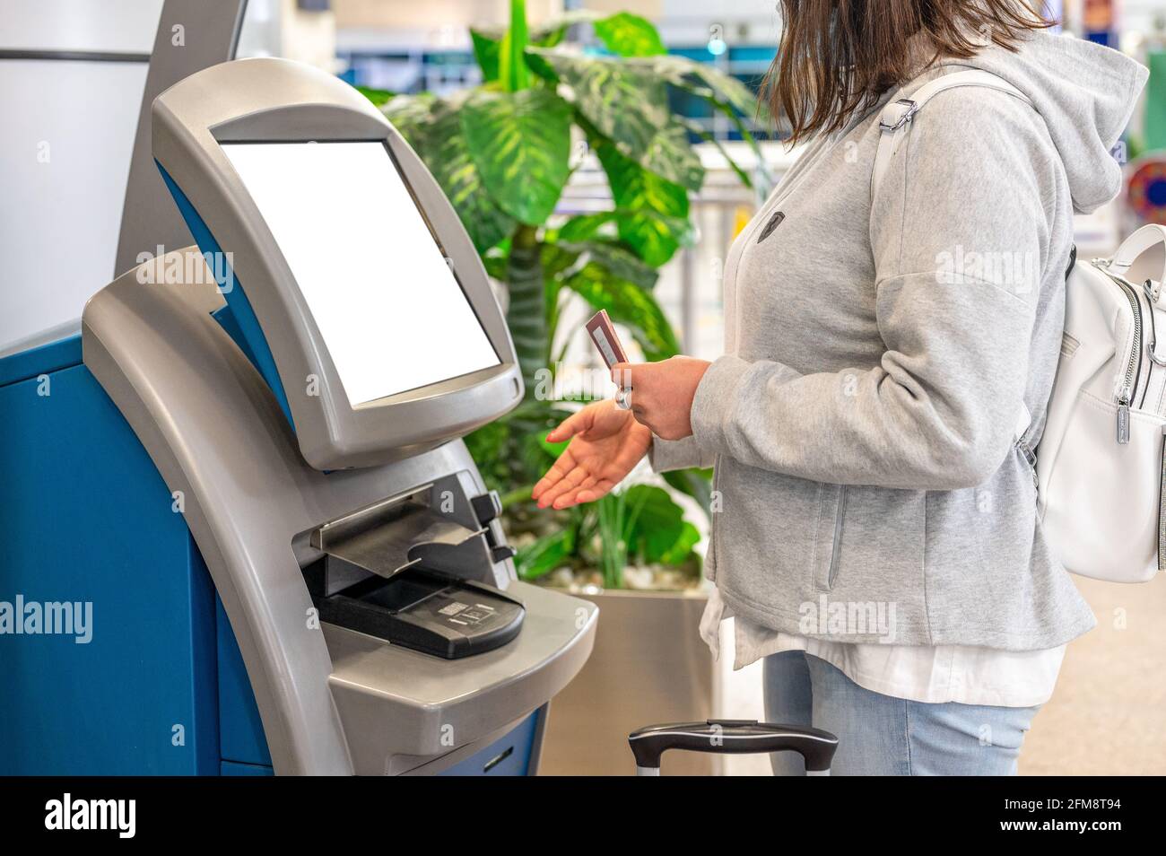 CAIRO, EGYPT - May 06, 2021: EGYPTAIR airline counter for self-check-in at Cairo airport. Woman using Self service machine and help desk kiosk at airp Stock Photo