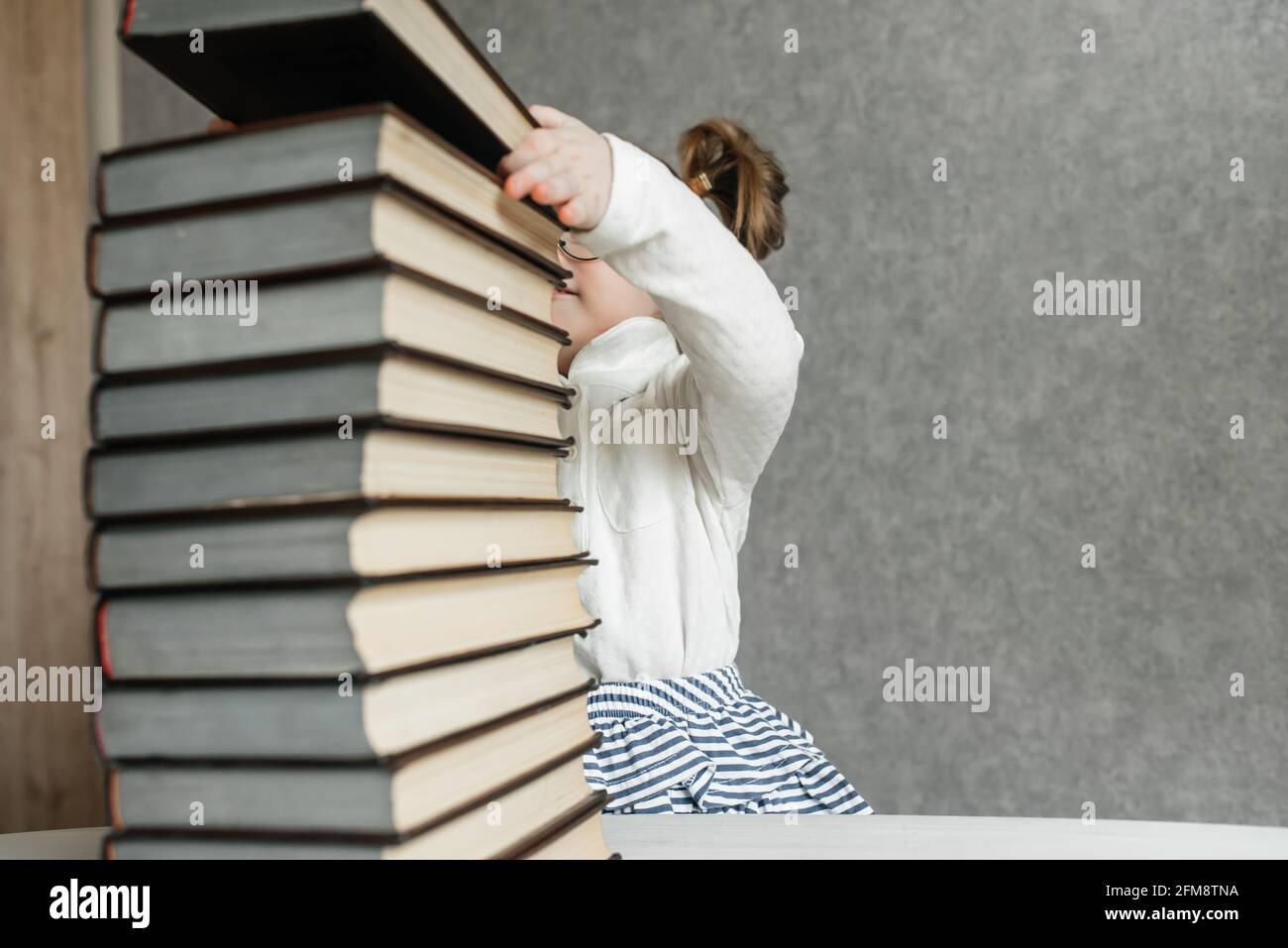 Cute kid girl preschooler with books at home Stock Photo - Alamy