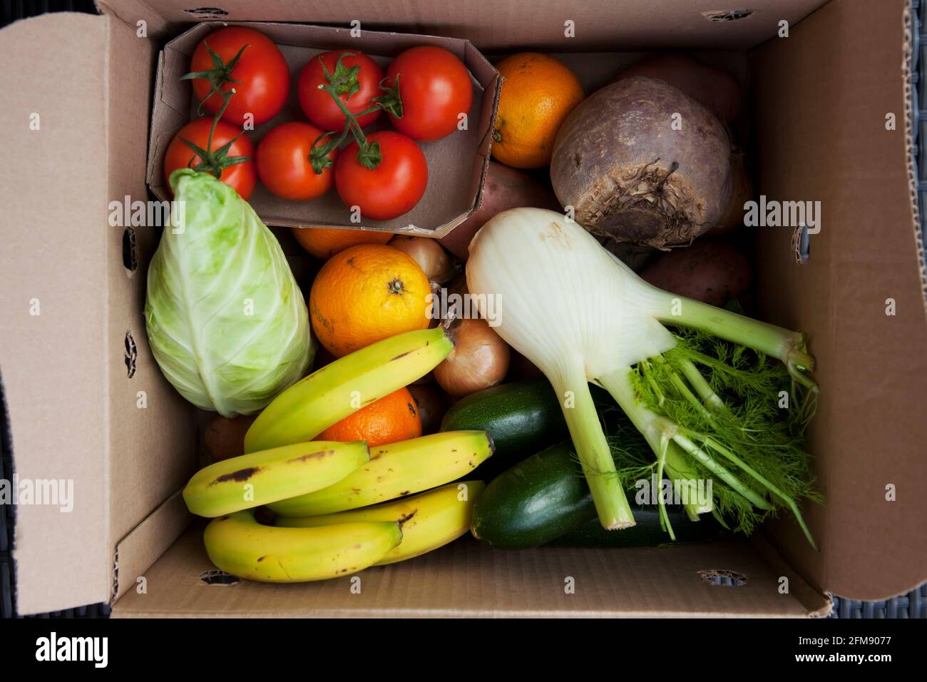 Inside the box: an organic vegetable delivery containing fruit and vegetables packed in a returnable / reusable box from Abel and Cole. Plastic free. Stock Photo