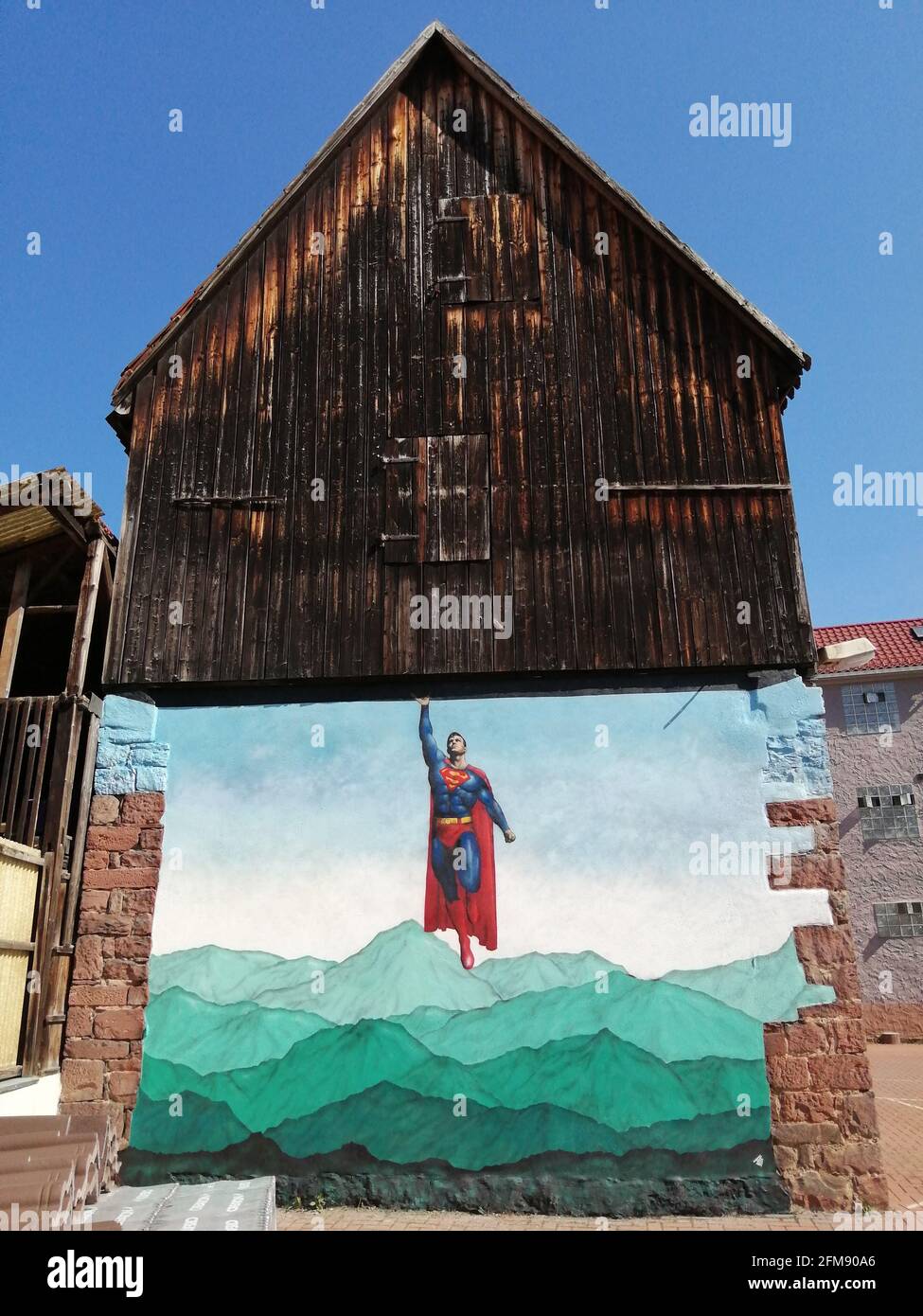 WESTON-SUPER-MARE, UK: Superman appearing to lift a house. THIS BRITISH graffiti artist has created a quirky series of mind-bending interactive street Stock Photo