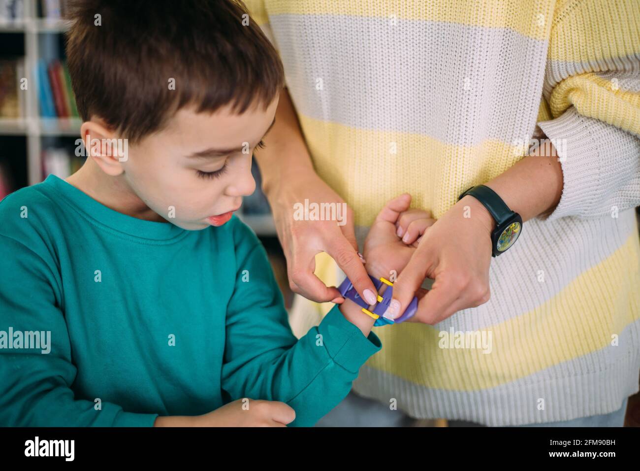 Mom gives her son his first watch. Learning to determine the time by the clock. Stock Photo