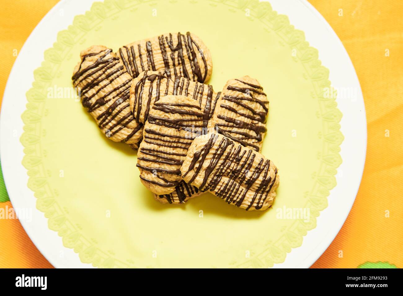 Butter cookies with chocolate on top on yellow background ready to eat. Concept of homemade food. Stock Photo