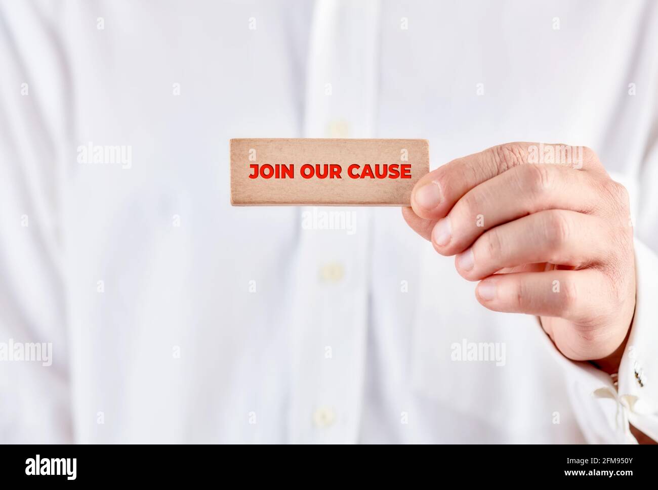 Male hand holds a wooden block with the message join our cause. Charity and relief work concept. Stock Photo