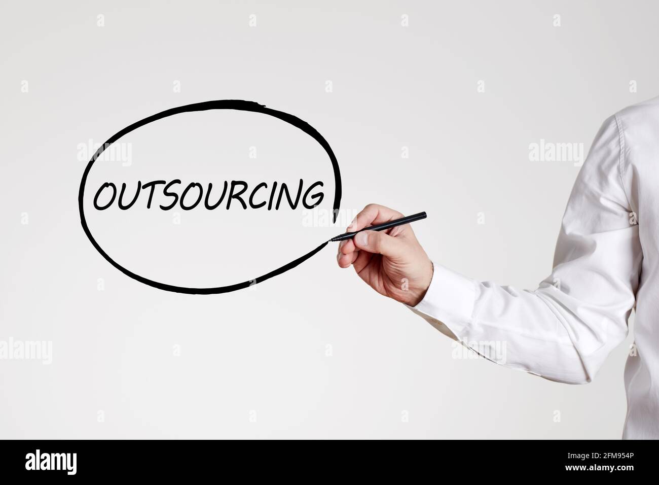 Businessman writes the word outsourcing with an outline circle. Business and technology concept. Stock Photo