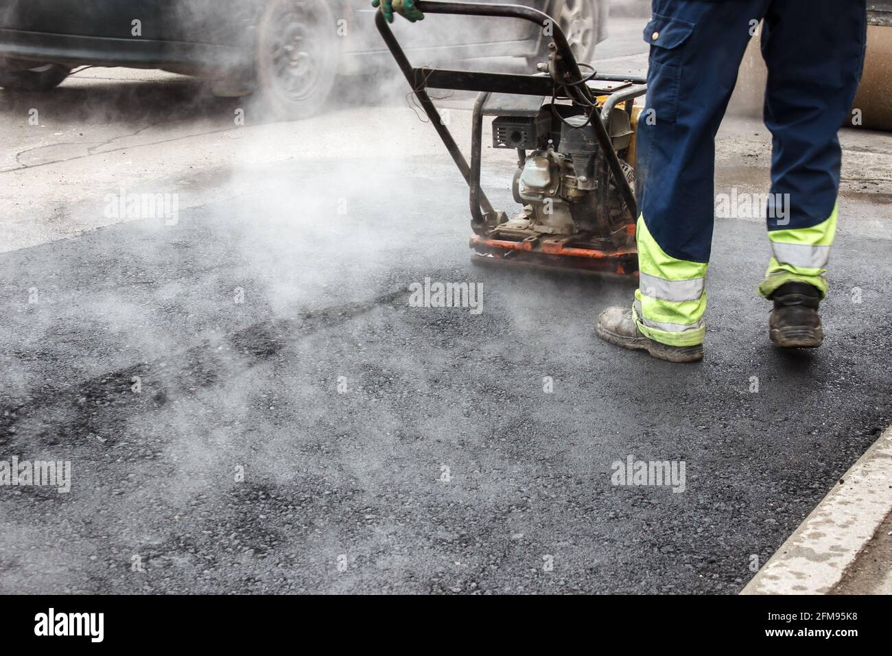 worker ramps the asphalt on the road with a mechanical rammer. laying the road surface. hot asphalt under the pressure of rammer Stock Photo Alamy