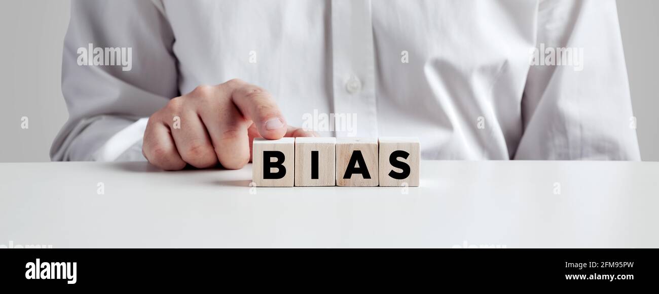 Businessman pressing his finger on the wooden cubes with the word bias. Racial or gender prejudice in workplace concept. Stock Photo