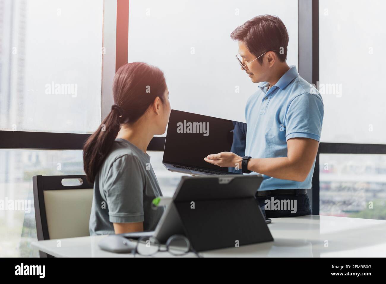 Businessman showing laptop display to woman colleague on work project. Stock Photo