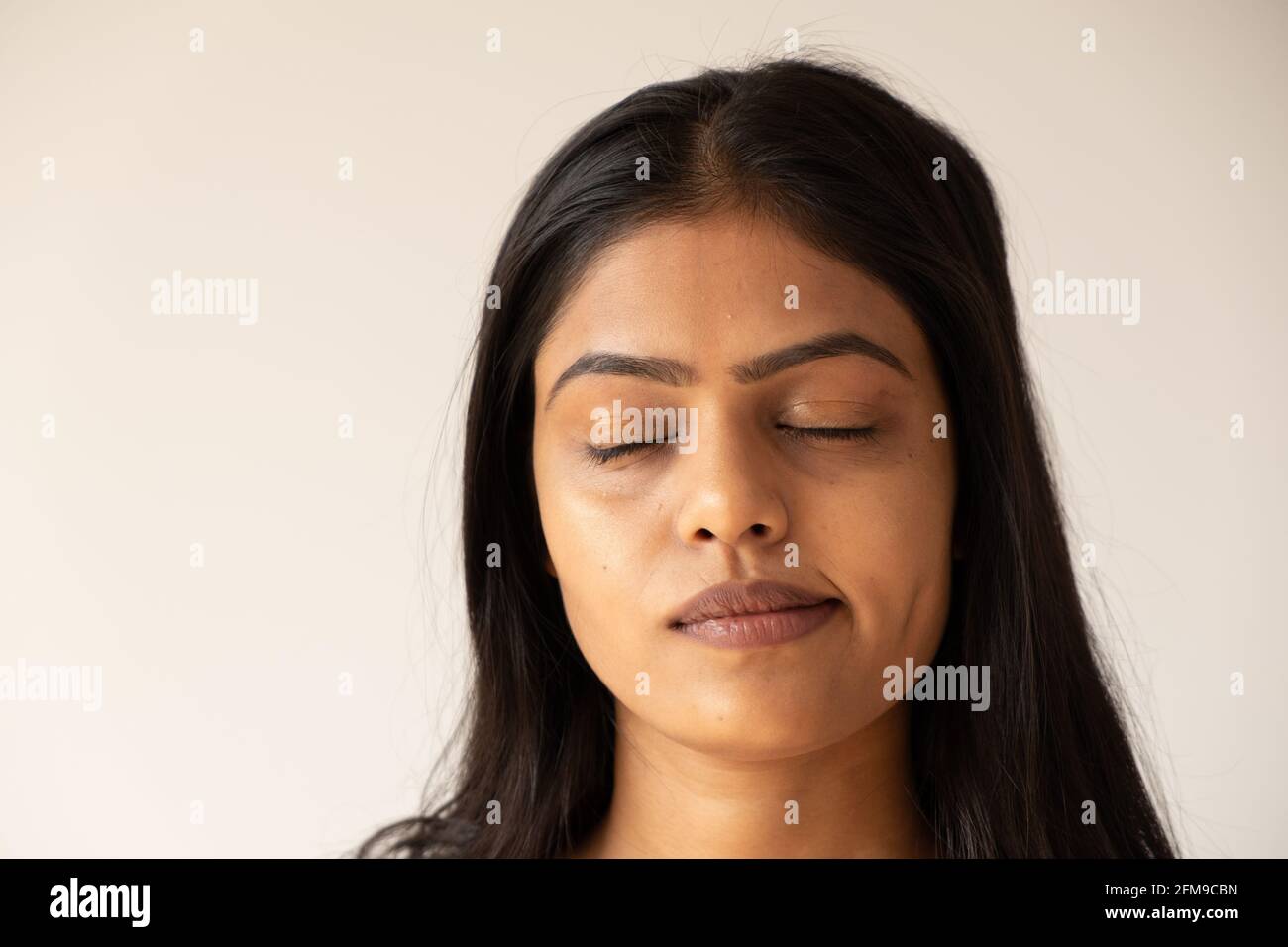 Closeup shot of a beautiful Asian girl with closed eyes isolated on a ...