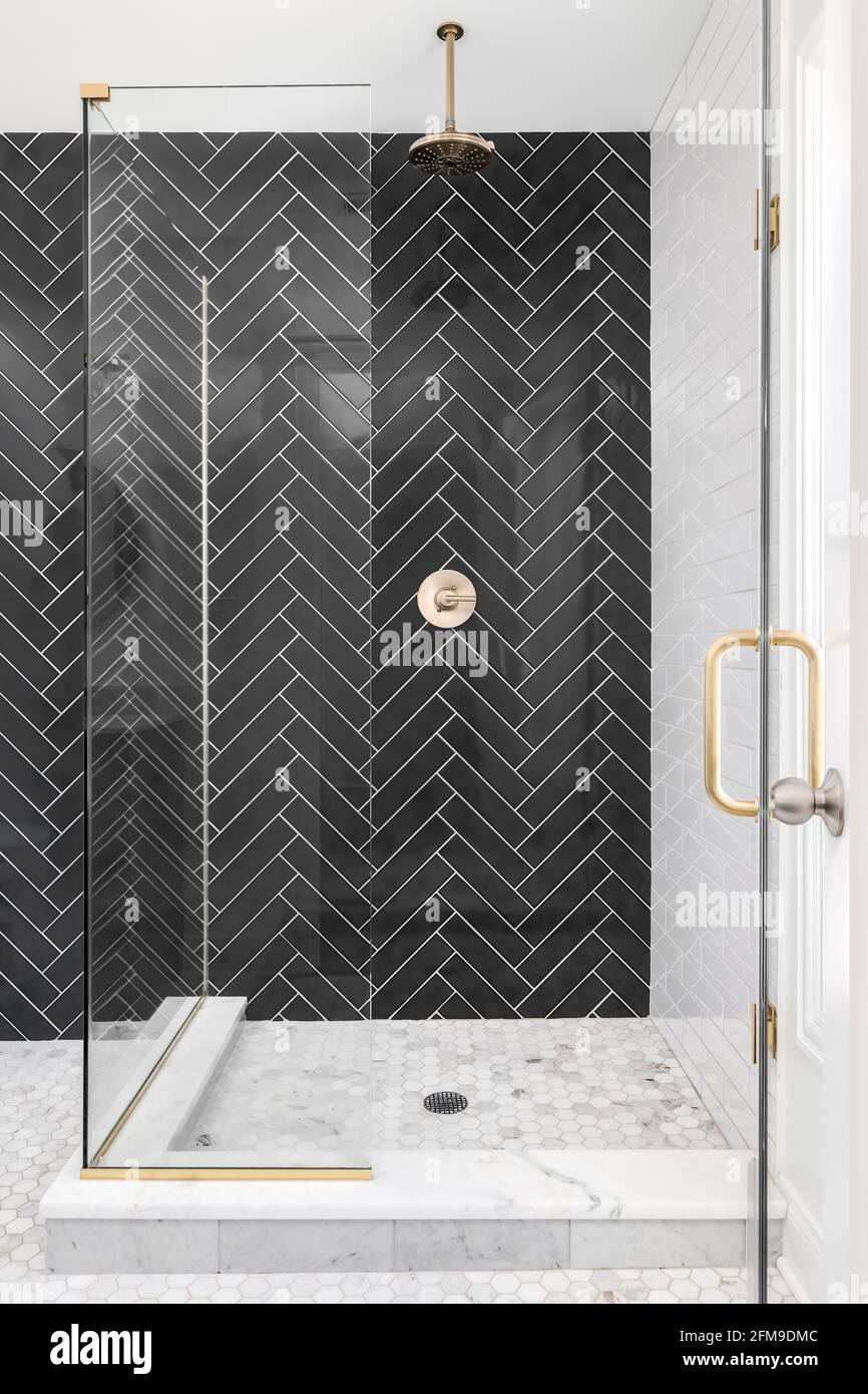 A black single herringbone tiled shower in a luxury home with gold