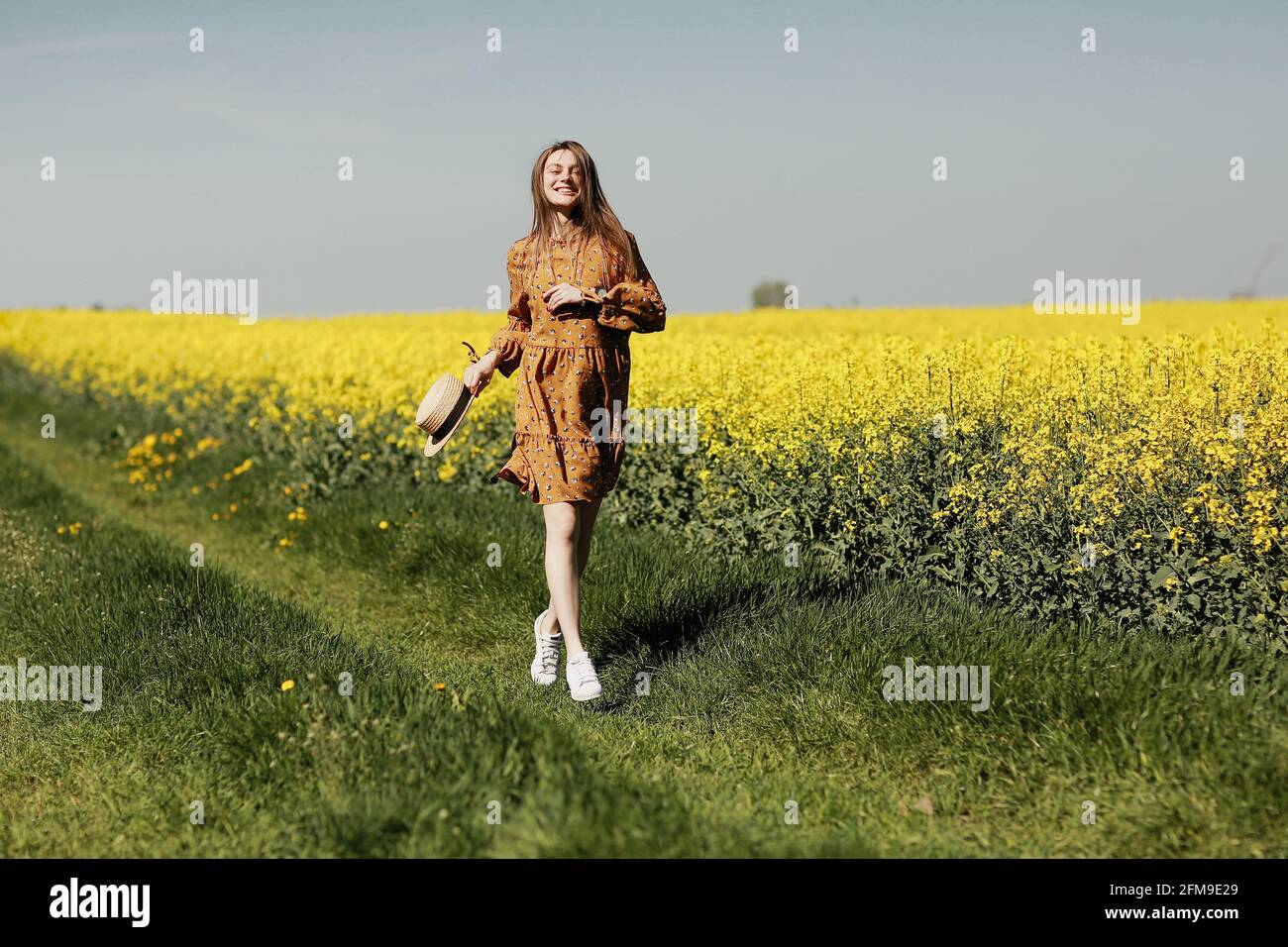 beautiful young woman walks in a field of yellow rapeseed. Girl ...