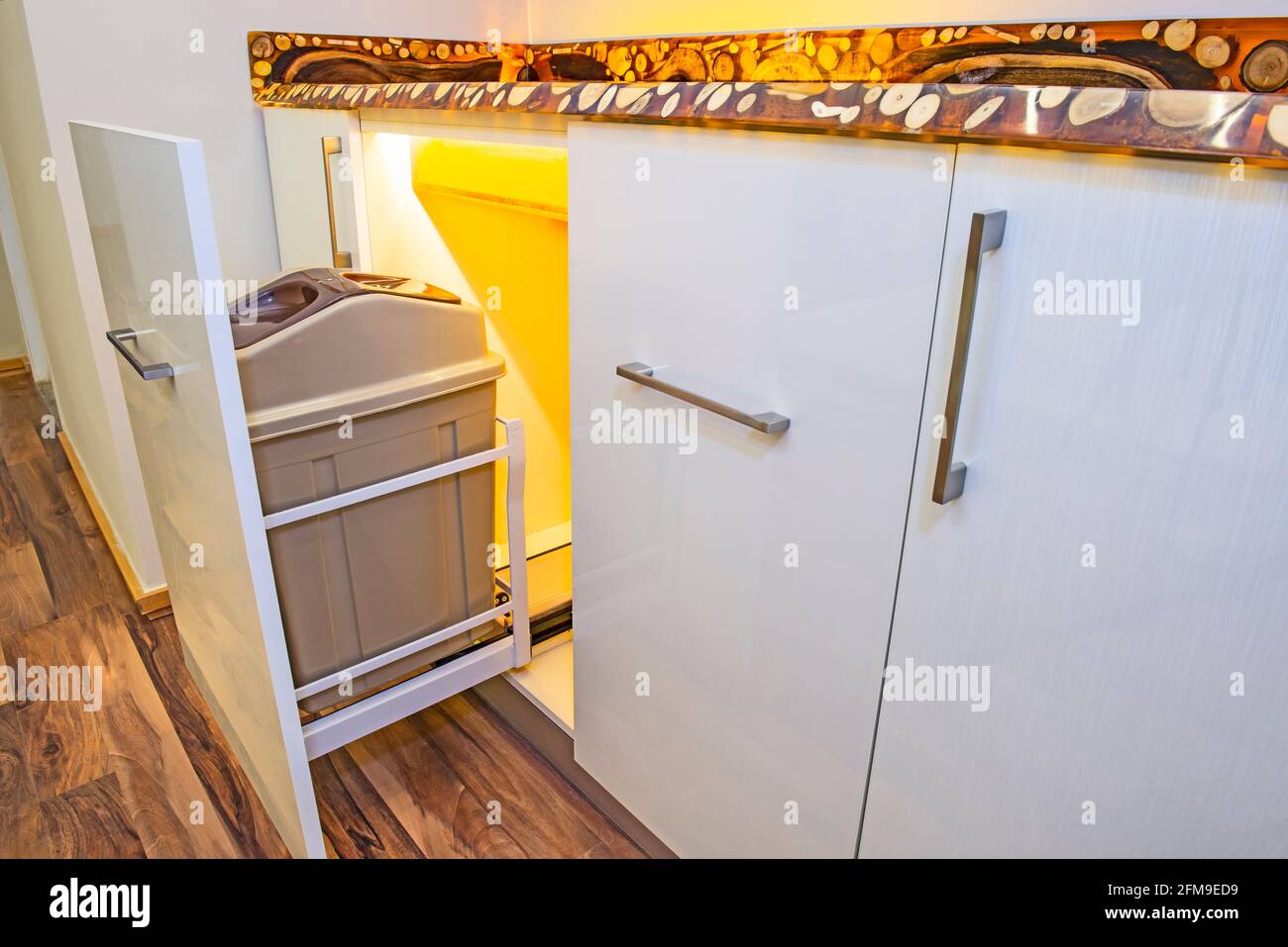 Interior design decor of kitchen in luxury apartment showing closeup detail of sliding cupboard with rubbish bin trash can Stock Photo