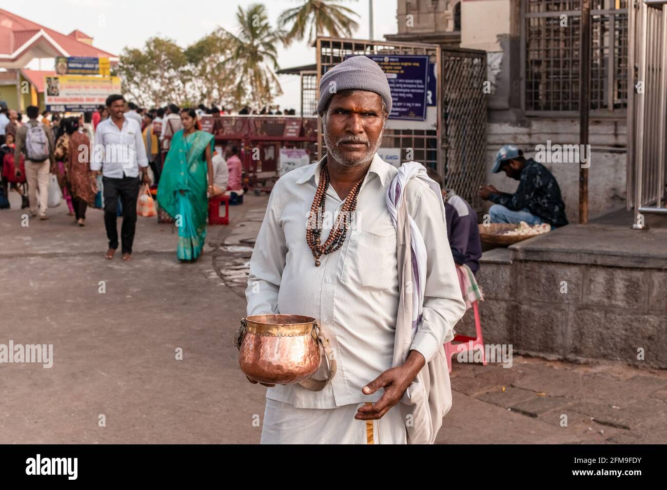 Mysuru, Karnataka, India - January 2019: An Indian man in traditional attire begging for alms at the ancient Hindu pilgrimage site of Chamundi Hills. Stock Photo