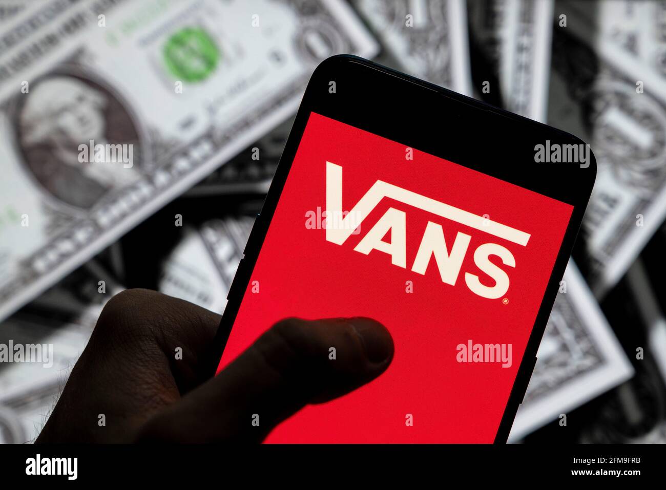 In this photo illustration the American skateboarding shoes and clothing  manufacturer Vans logo seen displayed on a smartphone with USD (United  States dollar) currency in the background. (Photo by Budrul Chukrut /