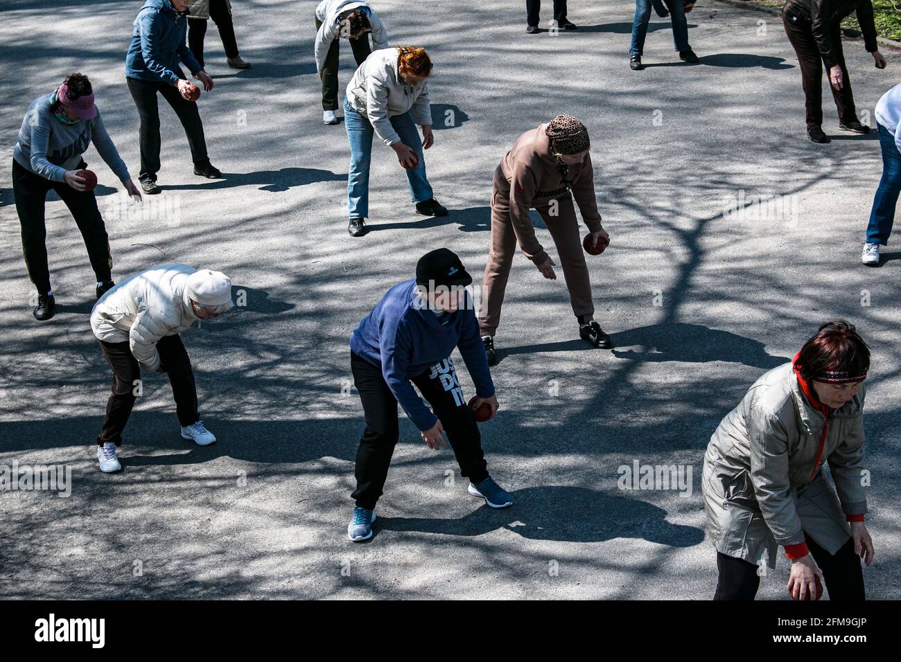 Dnepropetrovsk, Ukraine - 04.22.2021: A group of elderly people doing health and fitness gymnastics in the park. Old people do exercises with a ball. Stock Photo