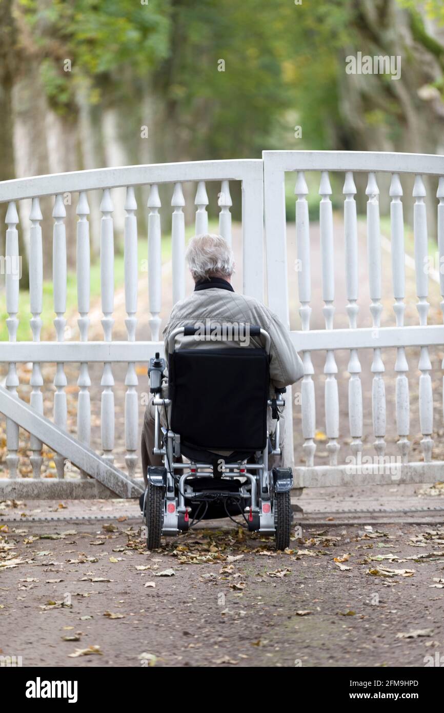 Wheelchair users in front of a locked entrance gate Stock Photo