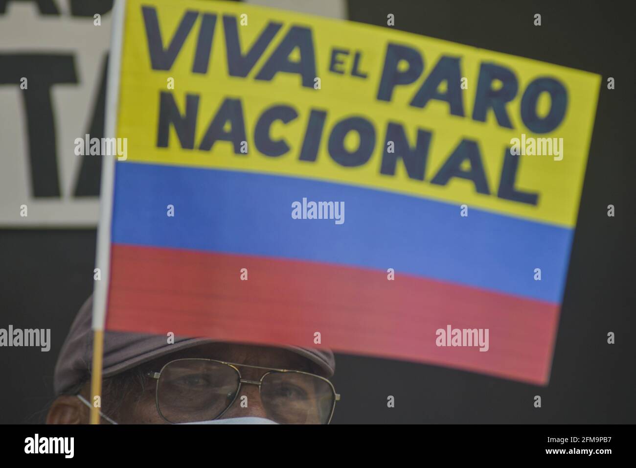 San Salvador, El Salvador. 6th May 2021. A man holds a Colombian flag with the message 'viva el paro nacional'. Salvadorans protest outside of the Colombian embassy in El Salvador against state repression against demonstrators in Colombia. More than 1,100 police brutality cases have been recorded since the begining of protest against a tax reform that would affect a majority of people in poverty and the middle class.  Credit: Camilo Freedman/Alamy Live News Stock Photo