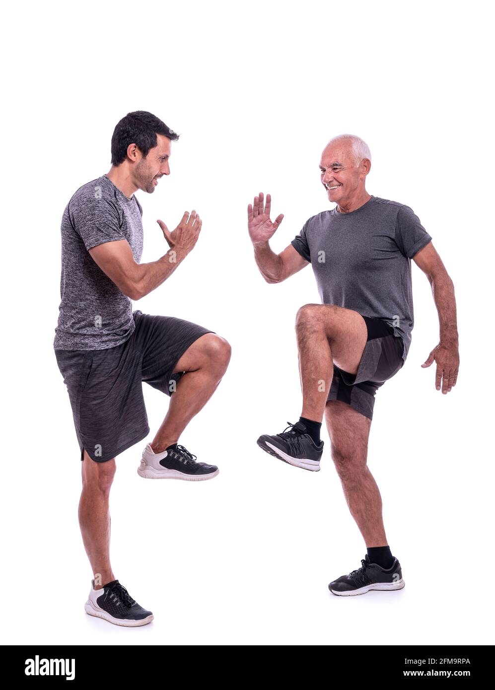 Elderly male client exercising with a fitness trainer, exercise walking in place, steps. On a white isolated background. Stock Photo
