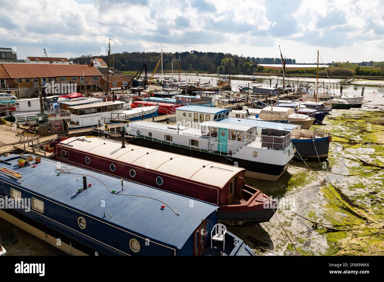 Woodbridge, Suffolk, UK April 30 2021: A grouping of house boats moored up on the River Deben in Suffolk at low tide Stock Photo