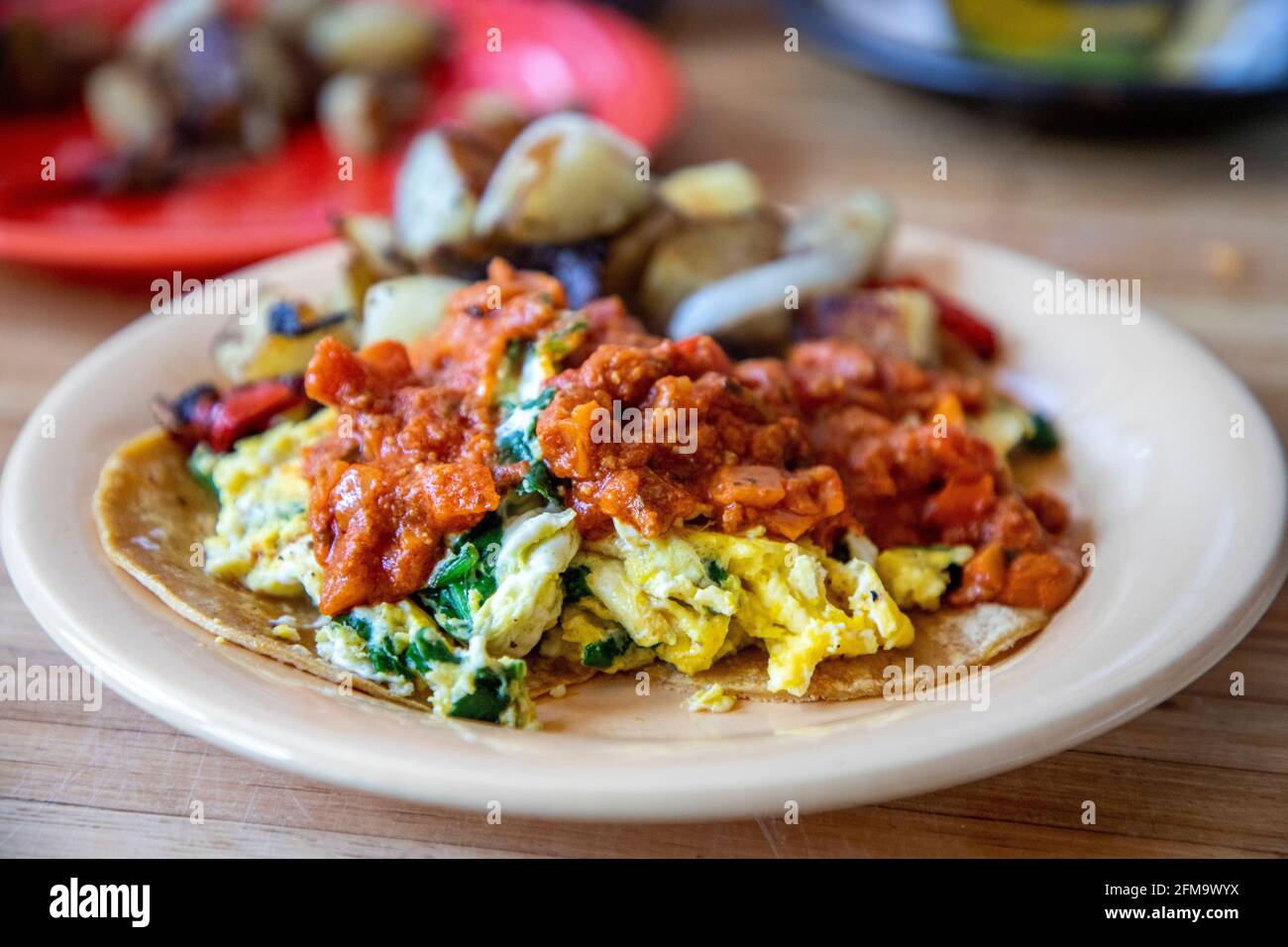 Homemade breakfast Chilaquiles with corn tortillas, scrambled eggs with
