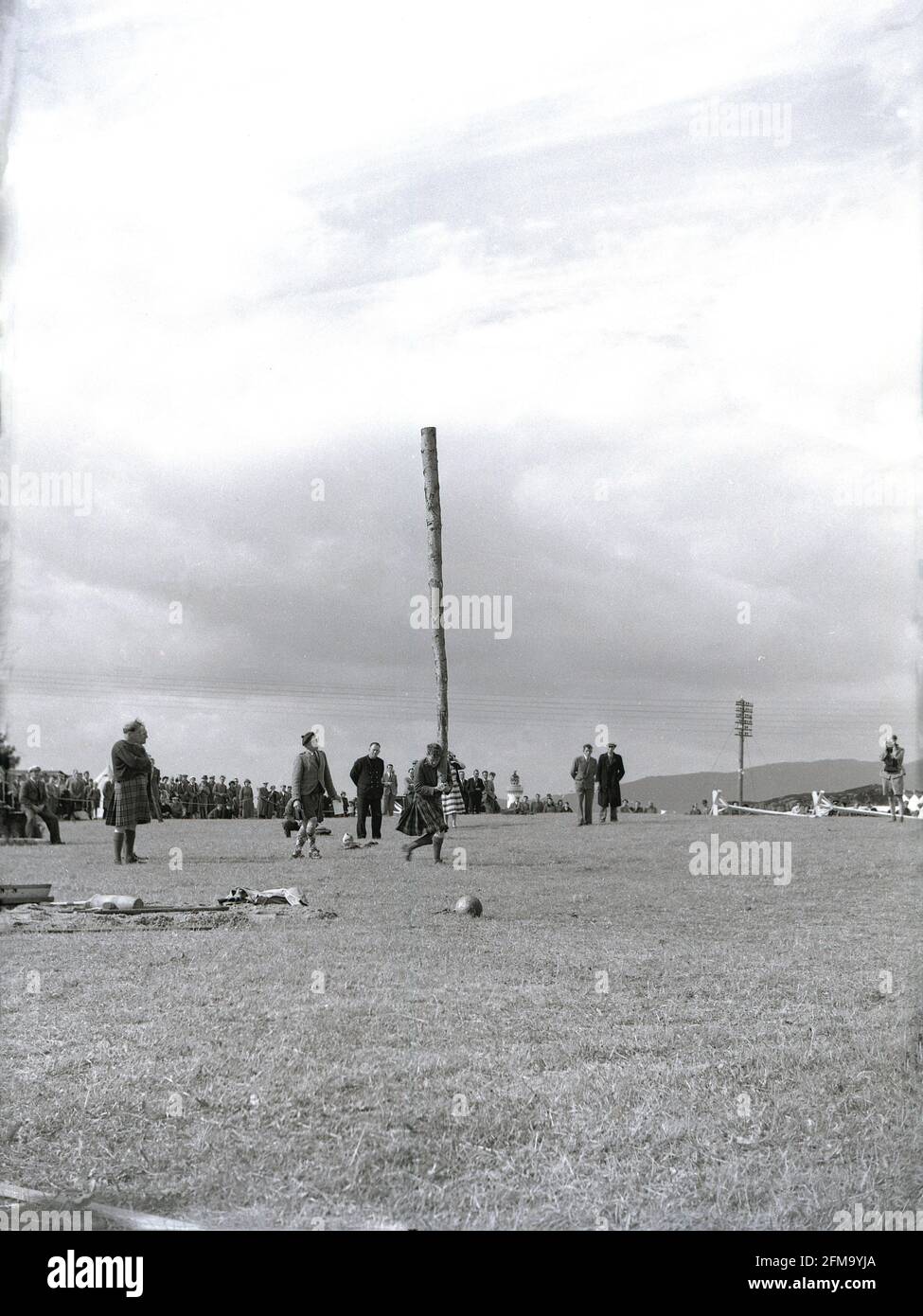 1956, a competitor at a highland games about to toss the caber, Scotland, UK. A traditional and well-loved athletic event at a Scottish highland games, the 'caber toss' involves a competitor tossing  long, heavy pole so that it turns end over end. Usually made from a Larch tree, and up to 20 feet in length, the caber is stood upright and then lifted up and tossed, not thrown. Caber is the Gaelic word for pole. Devised by Scottish woodsmen, the caber toss was first recorded in 1574, at a military meet  as toss 'ye barr', when clan warriors tested their physical strength in sporting contests. Stock Photo