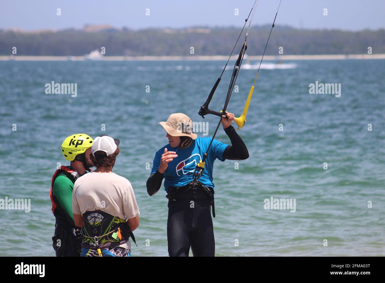 SYDNEY, AUSTRALIA - Dec 12, 2017: Three kite boarders standing on the beach.  One is holding the control bar and speaking to the other two. All are wea  Stock Photo - Alamy